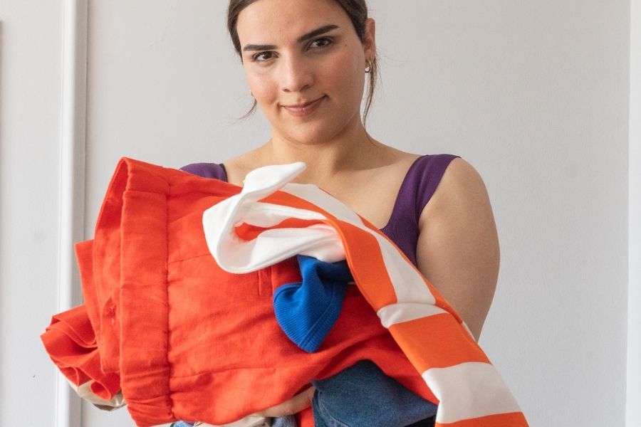Woman organizing colorful clothes for her capsule wardrobe collection