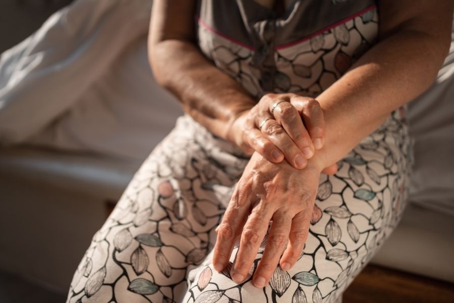 Woman demonstrating self-massage techniques on her hands in comfortable setting