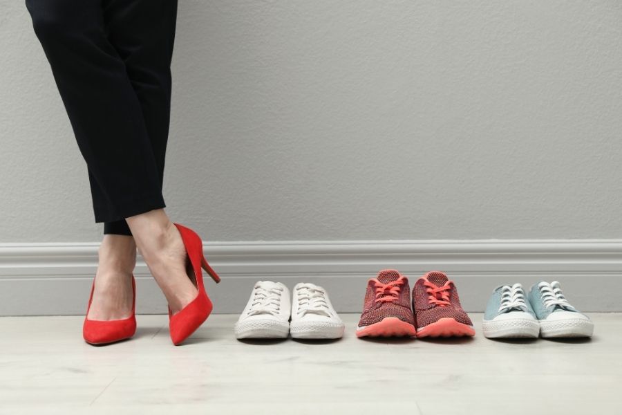 Woman in red heels choosing between comfortable heels and sneakers