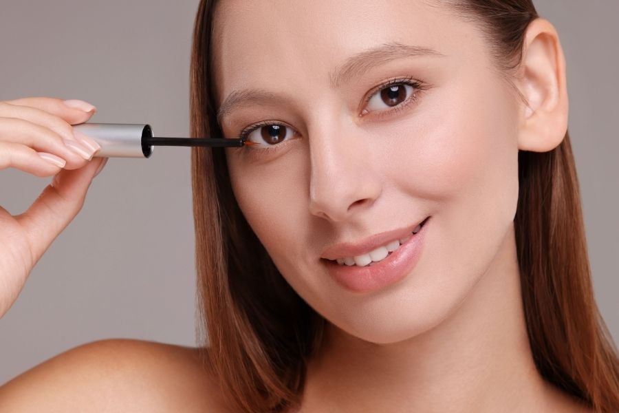 Woman applying eyelash growth serum with precision applicator for longer lashes