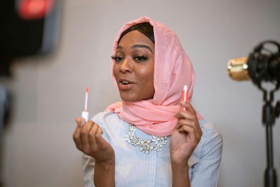 Beauty influencer demonstrating natural lip plumping techniques with lip gloss applicators