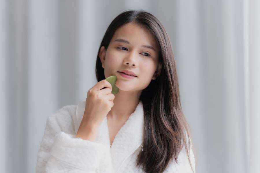 A woman using a facial tool to practice daily self care at home.